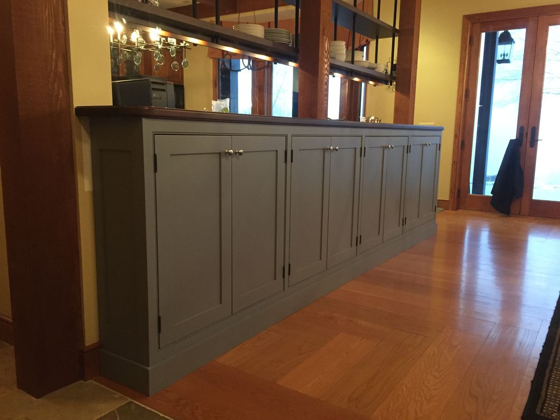Built-in dining buffet and bar with painted shaker doors and a walnut top